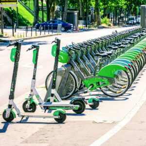A diverse group of people using e-bikes and e-scooters in a cityscape setting.
