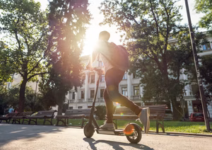A diverse group of people riding e-scooters on a city street.